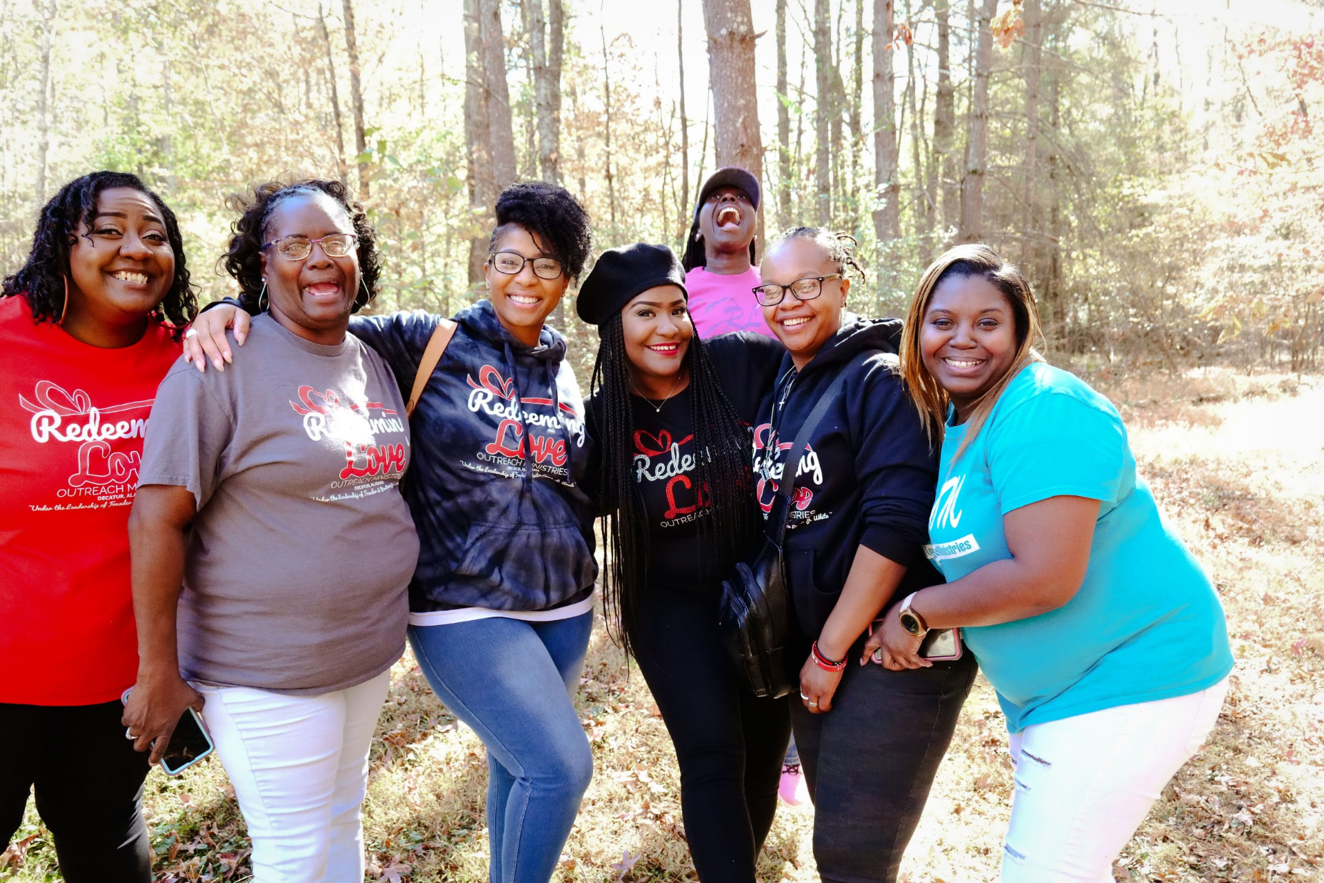 Group of women from the ministry smiling together outdoors on a fall retreat.