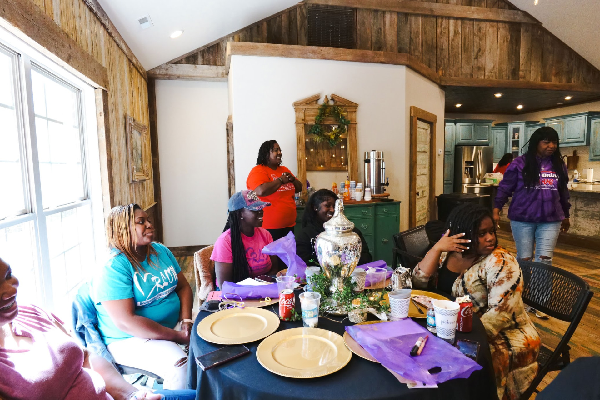 Women laughing and talking around a decorated table at a women's ministry brunch.